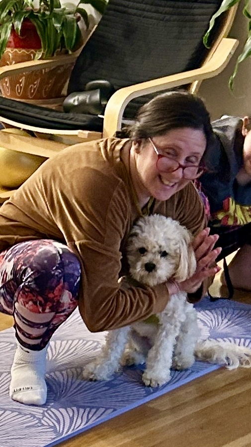 Woman in yoga position with dog between legs